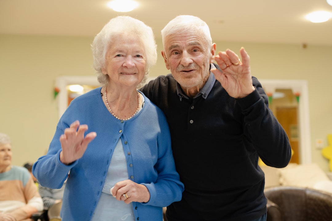 elderly-couple-waving-hello-in-a-room-nasfp-wpiti